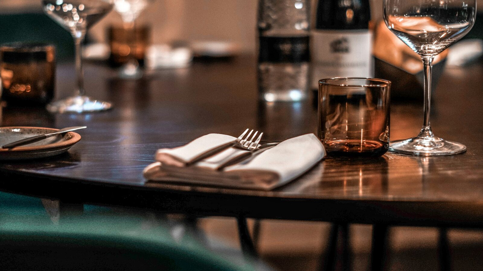 Lugar posto numa mesa de madeira escura, com copo de água e taça de vinho.