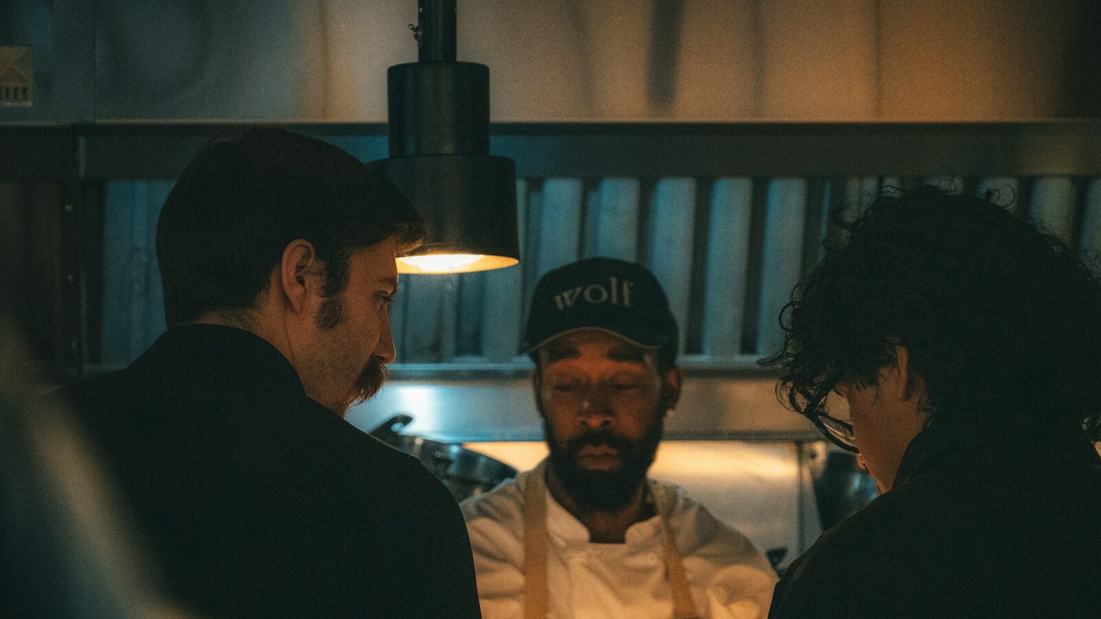 Equipe de restaurante conversando junto ao passe da cozinha.