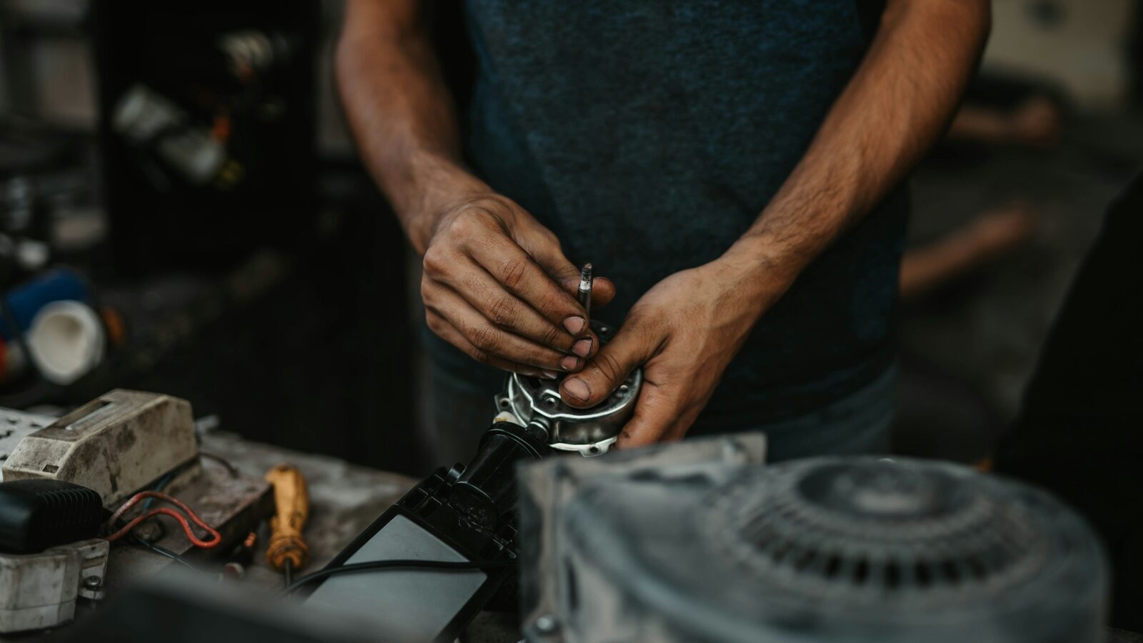 Técnico desmontando um motor sobre a bancada de uma oficina.